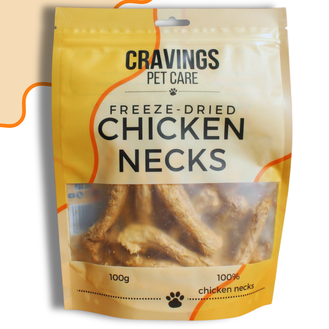 A stand-up pouch of Cravings Pet Care Freeze-Dried Chicken Necks, 100g. The packaging is primarily yellow and white with orange accents, featuring a clear window that displays the freeze-dried chicken necks inside.